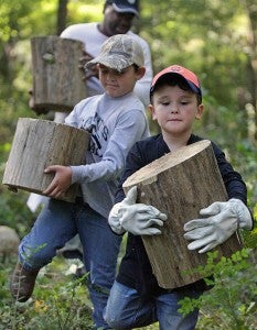 Landon Nichols, 6, right, and Nathan Austin, 8, carry pieces of a log Saturday morning while cleaning up a historic African-American cemetery as part of National Public Lands Day in the Vicksburg National Military Park. The holiday is the nation's largest single-day volunteer effort for public lands. (Justin Sellers/The Vicksburg Post)