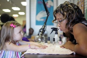 Shonna Morton, owner of Shonna's Nails and More, blows on the nails of Rileyanne Smithhart, 2, after painting them Saturday morning during the Shopping Extravaganza sponsored by Blackburn Nissan at the Outlets at Vicksburg. More than 500 ticketed shoppers turned out for the event which donated more than $13,000 to Hinds Community College DECA and Junior Auxiliary last year. (Justin Sellers/The Vicksburg Post)