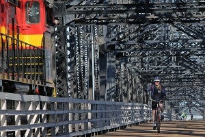 A cyclist waves to a train conductor Saturday morning on the Old U.S. 80 bridge during the 5th annual Bricks and Spokes bicycle ride. (Justin Sellers/The Vicksburg Post)