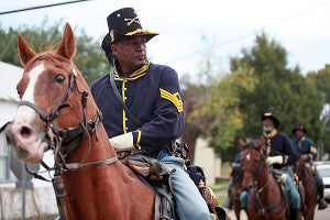 John Russell, portraying a first sergeant with the 3rd U.S. Colored Cavalry, leads other reenactors from Grove Street to the Jacqueline House Thursday for a re-enactment presentation. (Justin Sellers/The Vicksburg Post)