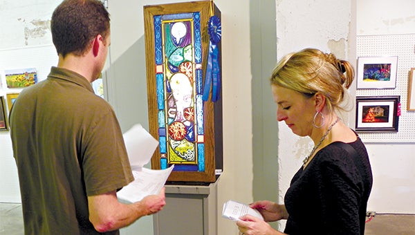 Aron and Kinga Shiers study the Best of Show “Bayou Nouveau: Luna’s Descent” by Mark Bleakley.