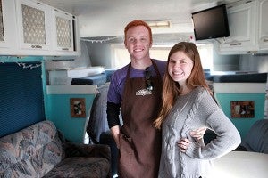 Documentary makers Alyssa and Heath Padgett stand inside their RV in the parking lot of the Outlets at Vicksburg after filming Wednesday at Rocky Mountain Chocolate Factory. The couple is filming a cross country documentary titled "Hourly America" in which they work hourly-wage jobs in all 50 states. (Justin Sellers/The Vicksburg Post)