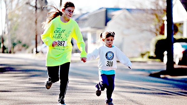 TOGETHER: Elaina Bailey, left, holds hands with her 4-year-old sister Samantha Bailey during the Chill in the Hills 1-mile fun run on Saturday. 