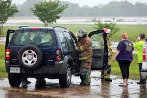 RESCUE: Vicksburg firefighters attend to a woman that they helped escape from her home on U.S. 61 South Monday after floodwaters began to approach the home. (Justin Sellers/The Vicksburg Post)