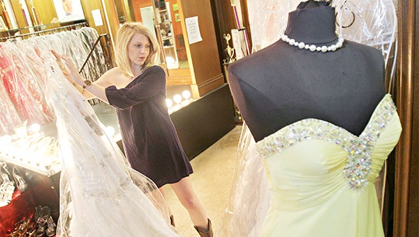 WOW FACTOR: Lurline Simmons, owner of Crown to Heels, holds dresses in Crown to Heels on Washington Street.