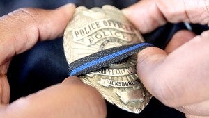 show of support: Vicksburg Police Officer Mario Grady places a black stripe over his badge Friday morning in a show of support and solidarity with those Dallas Police officers killed and injured during sniper attacks Thursday night.